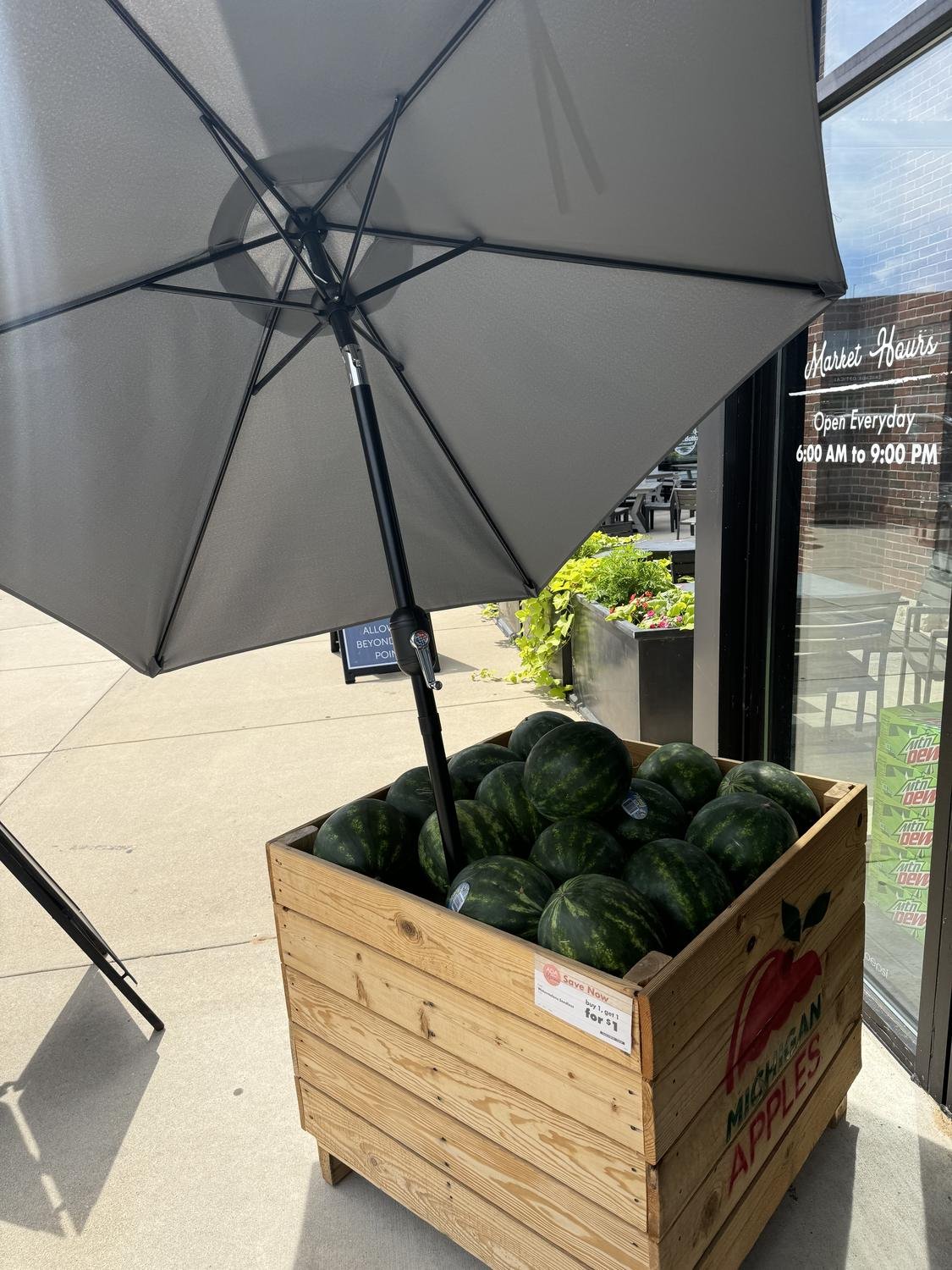 Umbrella mounted in a produce crate outside a grocery store